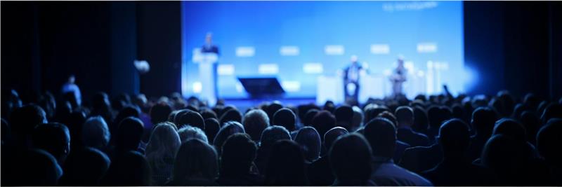 Stage setup at the SAP INDUS 2024 conference, featuring a large screen displaying the event logo and audience gathered for discussions on AI and cloud-driven business transformation.